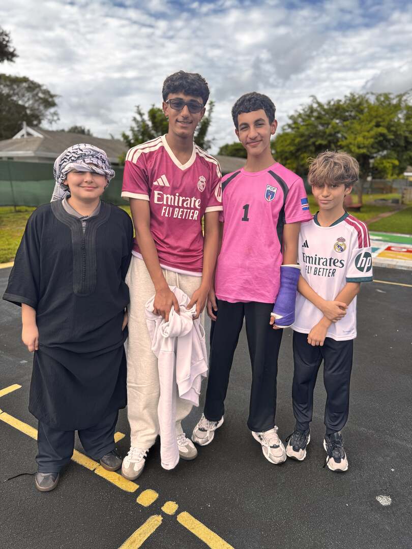 Friends in pink jerseys and a keffiyeh stand side by side on the court