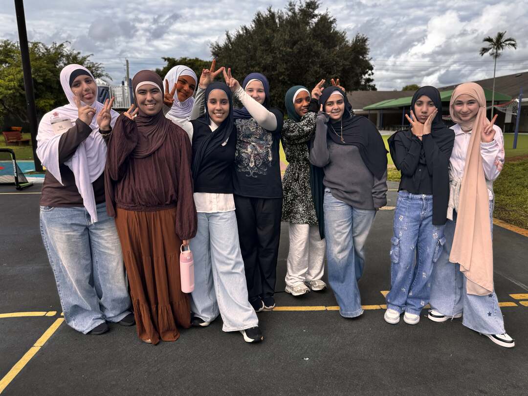 A cheerful crowd of friends in browns, creams and denim strike playful poses