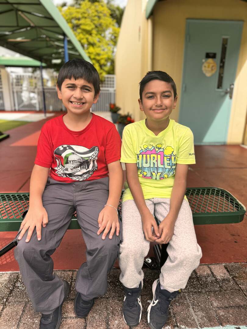 Two smiling friends in red and neon yellow tees sit side by side