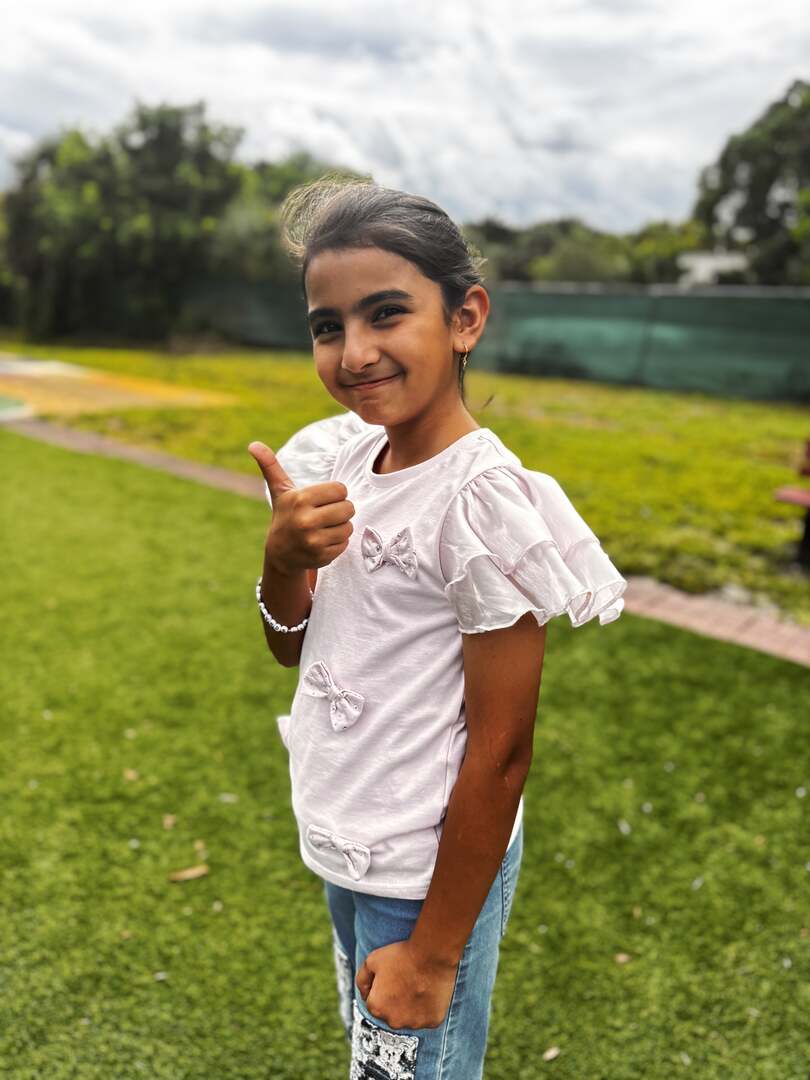 A thumbs up and a sweet smile in a ruffled pink top