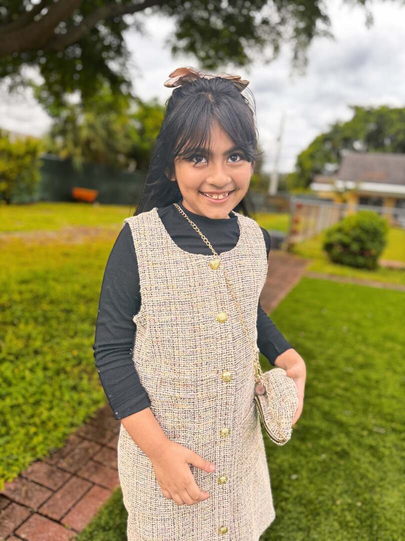 All smiles in a tweed dress and hair bow on the lawn