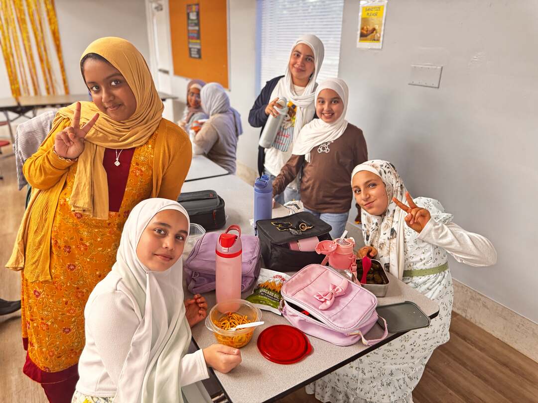 Friends in mustard and brown share lunch and peace signs on Dress Down Day