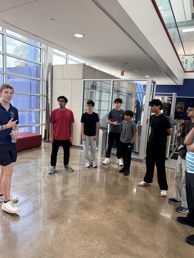 Students listening to a guide in a bright building lobby
