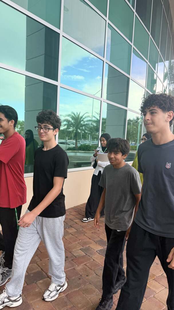Students walking past the glass walls of a campus building