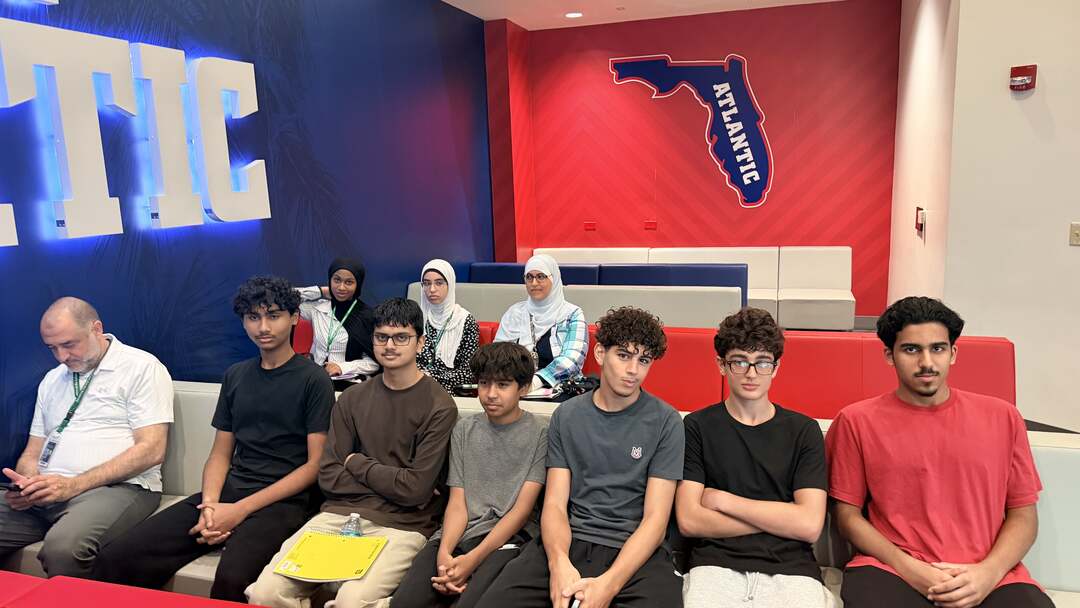 Students seated beneath the lit Florida Atlantic sign