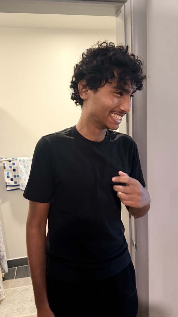 A student grinning in a dorm doorway