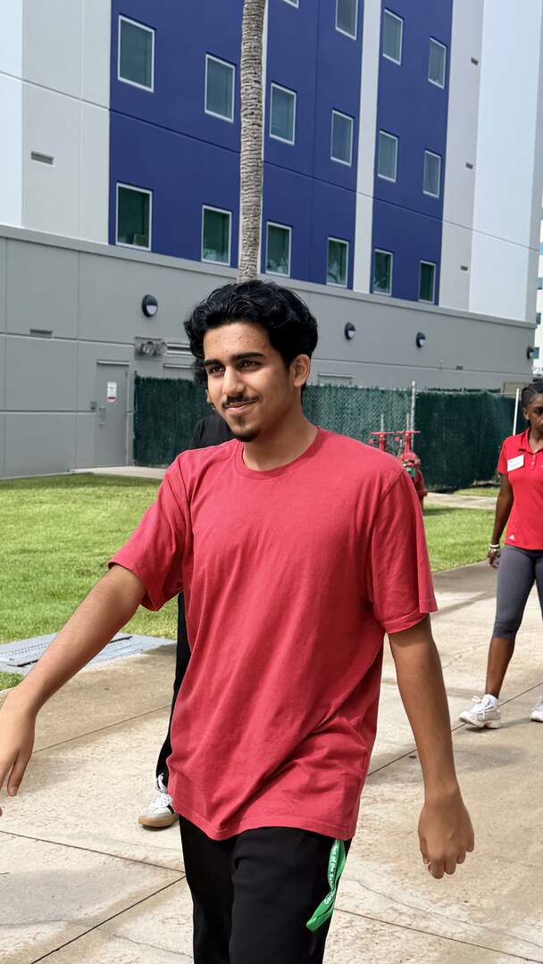 A smiling student walking outside a residence hall
