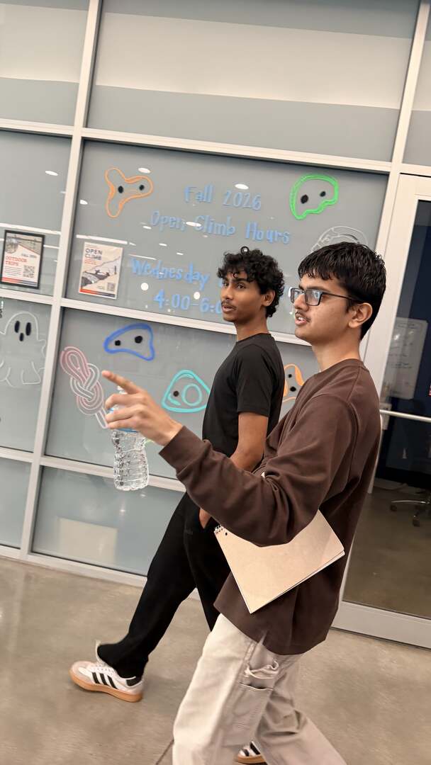 A student pointing out the climbing wall schedule