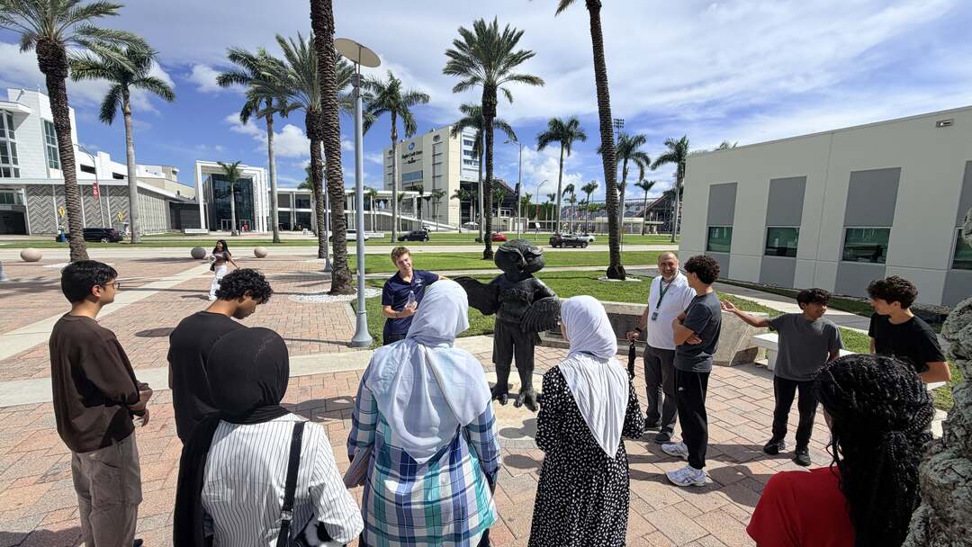 The group gathered around a guide on the palm-lined plaza