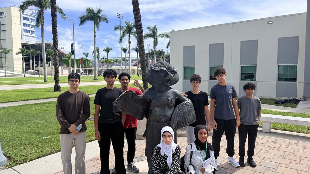 Students gathered around the bronze owl statue on the campus plaza