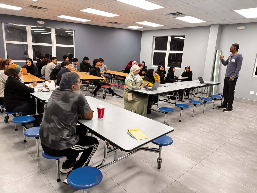 A wide view of the room with families seated for the presentation
