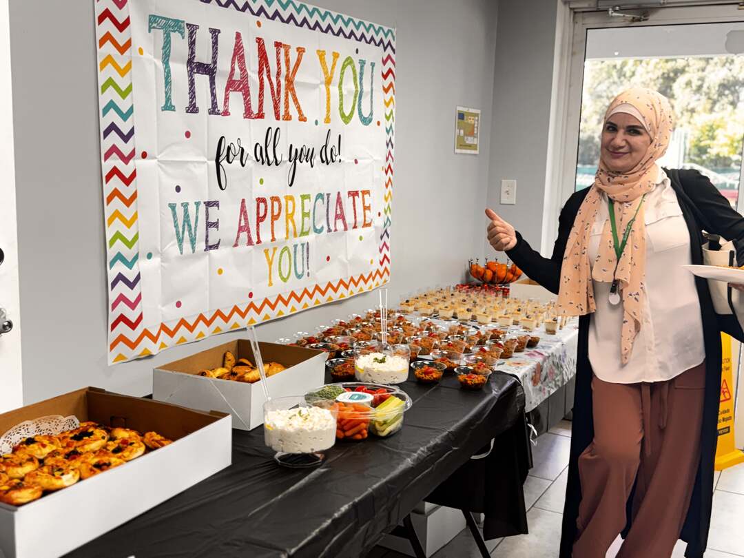 A staff member giving a thumbs-up beside the "Thank You, We Appreciate You!" banner